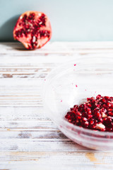 Pomegranate seeds on a glass bowl,on a white wooden board against a blue background