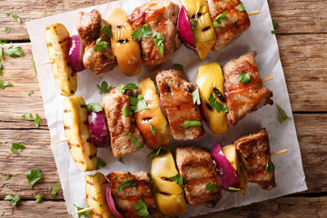 Pork skewers with apples and red onions close-up on the table. horizontal top view, rustic