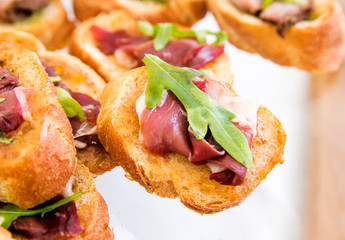 sandwiches with ham and arugula on a banquet table