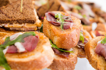 sandwiches with ham and arugula on a banquet table