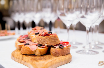 Snacks with ham on the banquet table and glasses of wine
