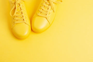 Pair of yellow shoes on yellow background. Trendy summer color, monochrome image. Hipster concept. Shot at angle. - obrazy, fototapety, plakaty