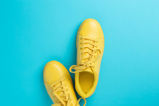 Pair of yellow shoes on bright blue background. Trendy summer color.