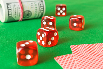 Dice, playing cards and twisted 100 dollar bills on the green table . The concept of winning. Casino