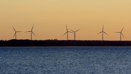 Turbiny wiatrowe na estońskim wybrzeżu Bałtyku, kręcące się z wolna podczas pogodnego, letniego wieczoru