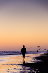 Fototapeta na wymiar Woman walking on the beach on the sunset