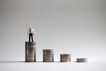 Four pile of coins and a miniature man.