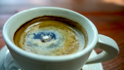 Close up of a cup of coffee with white cup on wooden background