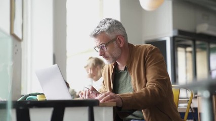 Man in trendy coffee shop working on laptop computer