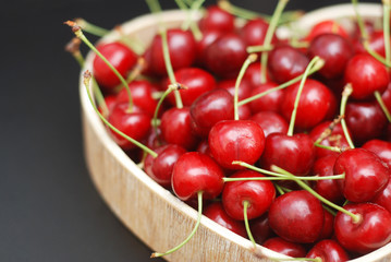 Fresh Cherries Fruit with leaves in Wooden Heart Shape Box, top view. Summer Red Berries. Black Background