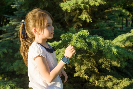Outdoor portrait in profile of a girl of 7 years. Copy space, background green tree