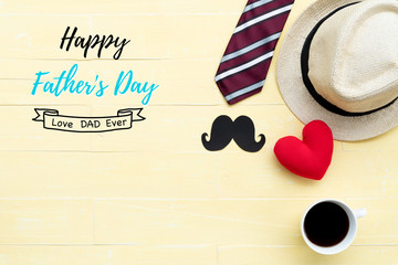 Happy fathers day concept. Red tie, handmade red heart, glasses, hat, black mustache and coffee cup on bright yellow pastel wooden table background.