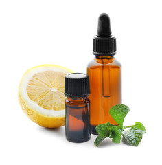 Bottles of citrus essential oil, mint leaves and lemon on white background