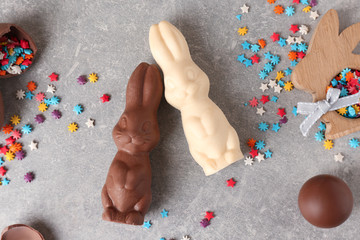 Beautiful Easter composition with chocolate bunnies, eggs and sprinkles on gray background