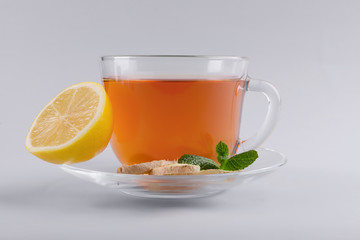 Cup of delicious tea with mint, ginger and lemon on grey background