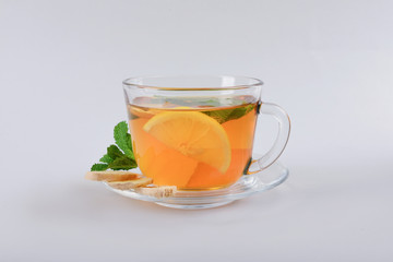 Cup of delicious tea with mint, ginger and lemon on grey background