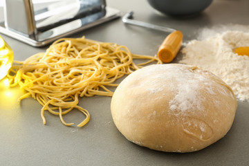 Raw dough and uncooked pasta on table