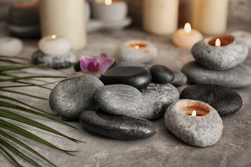 Beautiful spa composition with stones and candles on grey textured background