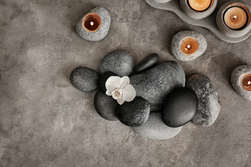 Beautiful spa composition with stones and candles on grey textured background