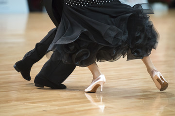 Beautiful womanish and masculine legs in active ballroom dance, indoors