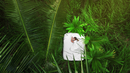 A hidden place. Sleeping woman in deep jungle forest lies on airbed,View from above