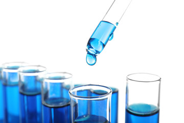 Dripping blue liquid into test tubes on white background