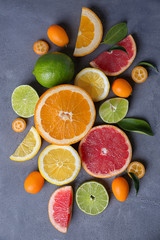 Slices of fresh citrus fruits on grey textured background