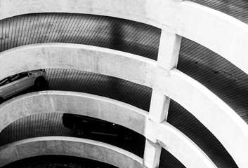 The architecture of the spiral curve and slope way to go to parking lot in the shopping mall. Car driving on concrete road on shopping mall building to car park.