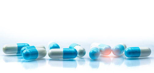 Blue and white capsules pill spread on white background with shadow and copy space. Global...
