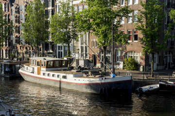 Fototapeta na wymiar On the banks of the canals of Amsterdam, magnificent boats are transformed into houses