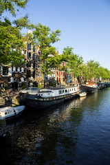 Fototapeta na wymiar On the banks of the canals of Amsterdam, magnificent boats are transformed into houses
