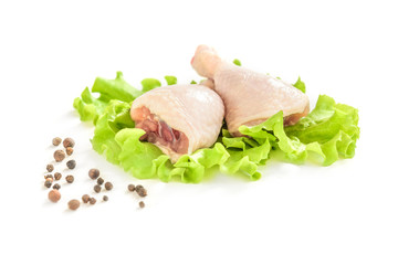 Raw chicken legs and green salad isolated on white background.