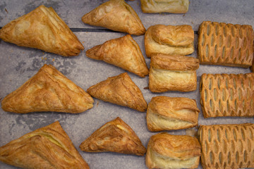 Puff pastry rolls. fresh sweet baking on papyrine. Several kinds of crispy pies lie in rows on a baking sheet on the counter. Top view, tasty delicious, dessert background