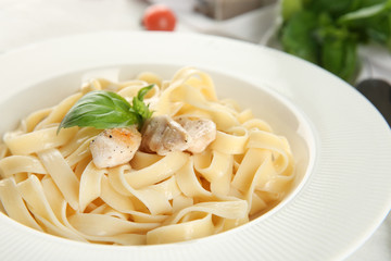 Plate of tasty pasta with chicken fillet on table, closeup