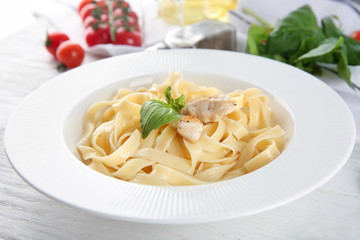 Plate of tasty pasta with chicken fillet on table