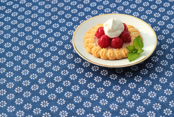 rasperry tart on blue tablecloth with flowers