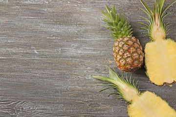 Whole and cut ripe pineapples on wooden background