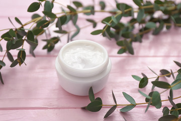 Obraz na płótnie Canvas Jar of moisturizing cream with herbal extract on wooden table