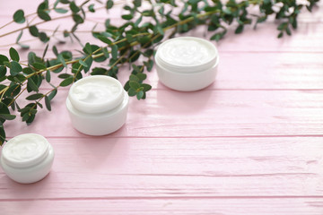 Obraz na płótnie Canvas Jars of moisturizing cream with herbal extract on wooden table