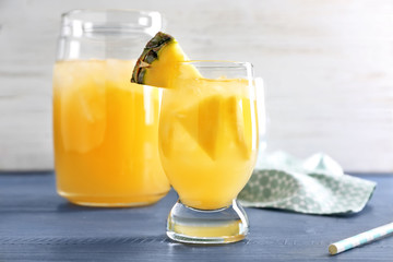 Glass of tasty fresh pineapple juice on wooden table