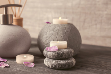 Spa stones with candles and cosmetics on wooden table