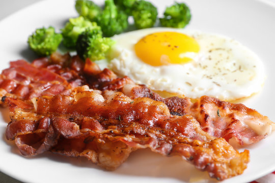 Fried bacon rashers and egg on plate, closeup
