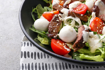 Tasty salad with meat, cherry tomatoes and mozzarella on plate