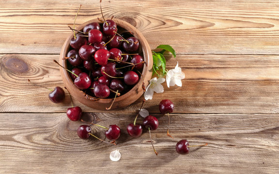 Fresh cherry in a wooden bowl on a rustic background. Top view