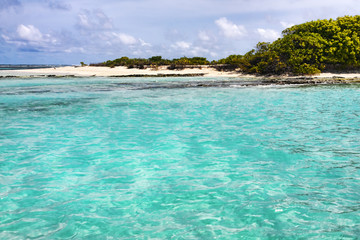 Approach to an uninhabited atoll in the Maldives islands with white sand and coral reefs