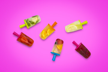 Homemade fruit popsicle on a pink background. Strawberry, Lemon, Lemon with mint, Orange, Cherry, Multifruit. Flat lay, top view