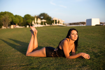 happy beautiful woman in bikini on the green grass on sunset.