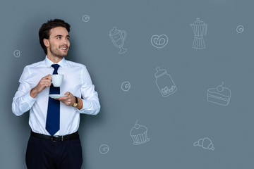 Drinking coffee. Cheerful clever lawyer looking elegant and feeling relaxed while drinking tasty coffee