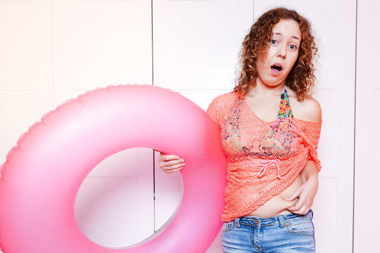 Woman point to her belly and hold an inflatable round. Preparing for the vacation, diet concept, unready for vacation
