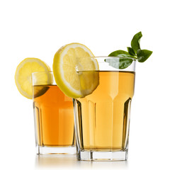 two glasses full of ice tea with lemon slices and tea leaves on white background